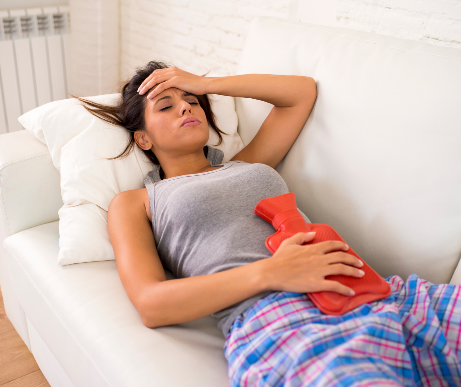 Woman lies on sofa with a hot water bottle for period pain